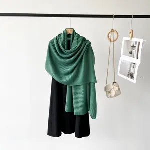 Detail view of a forest green pleated scarf draped elegantly over a black dress.