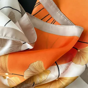 Elegantes Seidentuch in Orange mit zartem Ginkgoblatt-Druck, luxuriöser und weicher Griff.