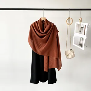 Detailed texture view of a burnt orange pleated scarf draped elegantly over a black dress