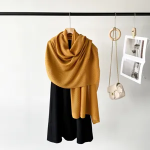 Detailed view of a solid yellow pleated scarf elegantly draped on a hanger with accessories.