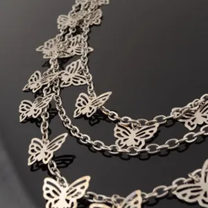 Detailed view of trendy multi-layer silver metal chain with hollow butterfly charms.