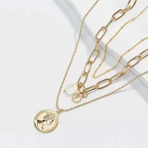 Vue de détail du collier chaîne or multicouche avec perle baroque et pendentif pièce.