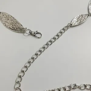 Λεπτομέλεια ασημένιας μεταλλικής αλυσίδας μέσης με φύλλα, κομψή γυναικείο ζώνη.
