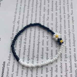 Primo piano braccialetto margherite di perline bianco nero, dettaglio di gioielli floreali.