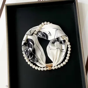 Detail view of stylish silk scarf with pearl magnetic necklace, elegant black and white print.