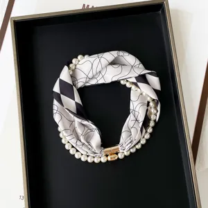Detailed view of pearl silk scarf necklace with magnetic clasp, black and white printed design.