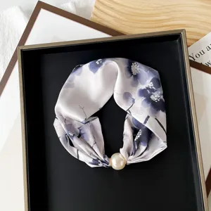 Chic floral print silk scarf with large pearl magnetic clasp detail, elegant neck and hair accessory.