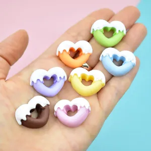 Makroansicht bunter Herz-Donut-Anhänger aus Harz in der Hand für DIY-Handyhüllen-Dekoration.