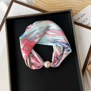 Close-up detail of a floral printed silk neck scarf with an elegant pearl magnetic buckle.