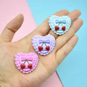 Close-up of heart-shaped resin charms with cherry and bow details in macaron colors