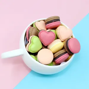 Macro view of colorful heart and round macaron resin charms stacked inside a white cup