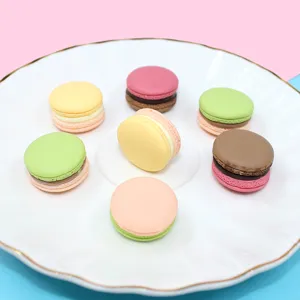 Close-up of colorful 3D resin macaron charms for DIY crafts on a white porcelain plate