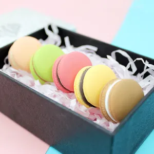 Close-up of five colorful 3D macaron resin charms in a black decorative gift box