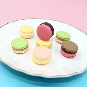 Close-up view of colorful resin macaron DIY charms on a white plate with gold-rimmed edges