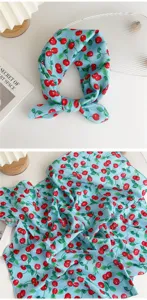 Light blue cotton linen scarf detail showing cute red cherry print and soft fabric texture.