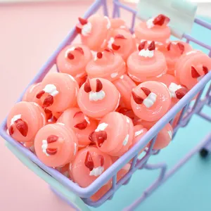 Detailed view of pink resin cake charms for DIY crafts inside a mini purple shopping cart