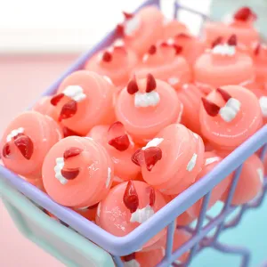 Close-up of pink resin devil cake charms in a mini purple shopping cart for DIY crafts