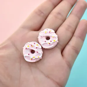 Detailed view of miniature pink resin donuts featuring white icing and colorful sprinkles