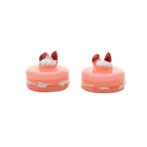 Two miniature pink resin macaron charms with strawberry cream topping detail