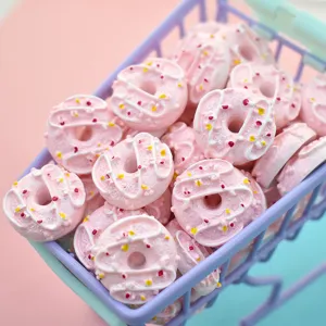 Close-up detail of miniature pink resin donuts with white icing and colorful sprinkles.