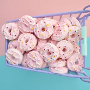 Macro view of miniature pink resin donuts in a purple toy cart for DIY crafts decor