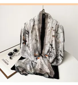 Close-up detail of satin square scarf with elegant floral bird print and geometric border.