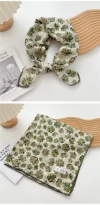Dettaglio del foulard floreale in cotone e lino, con trama del tessuto e bordo in pizzo verde.