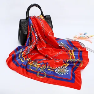 Detail view of red square satin silk scarf with elegant chain and baroque equestrian print.