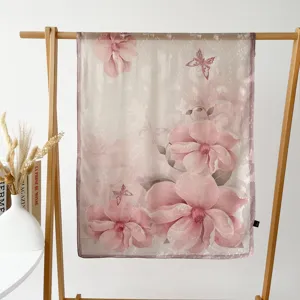 Detailed view of the pink floral sheer scarf hanging on a wooden rack with decor.