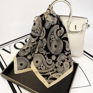 Detailed close-up view of the luxurious black and beige paisley print silk square scarf.