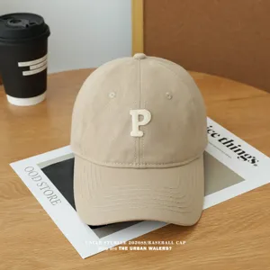 Detailansicht der beigen Baseballkappe mit weißem Stickbuchstaben P, weicher Stil.
