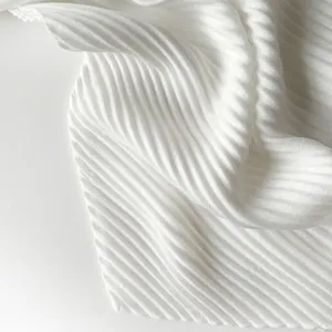Detailed view of white pleated scarf fabric showcasing fine texture and elegant folds.