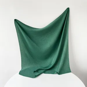 Dark green pleated square scarf detail showing delicate fabric texture and elegant drape.