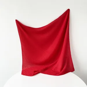 Detail view of the vibrant red pleated square scarf showcasing fine texture and craft.
