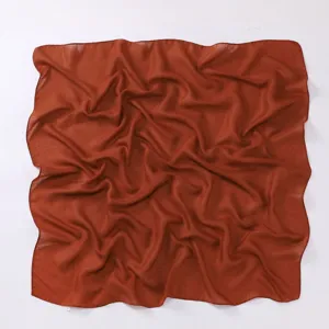 Detail view of the solid color cotton linen square scarf in rust red, showcasing soft draped texture.
