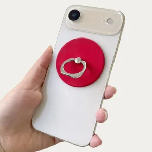 Detailed view of a red magnetic phone ring holder with silver ring on a white phone case
