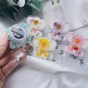 Vista dettagliata dei porta badge a forma di elefante con fiori secchi e clip sul retro