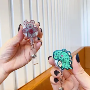 Close-up view of cute cartoon teddy bear and dinosaur graffiti style retractable badge reels