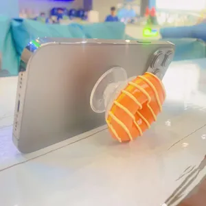 Nahaufnahme einer realistischen Donut-Handyhalterung, die ein Smartphone stützt