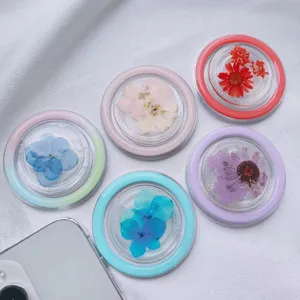 Close-up of circular phone grips with embedded real dried flowers in various vibrant colors.