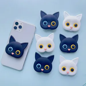 Close-up of cute black and white cat-shaped phone socket grips arranged on a blue background