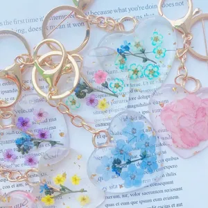 Macro view of heart-shaped resin keychains with real dried flowers and gold flakes.