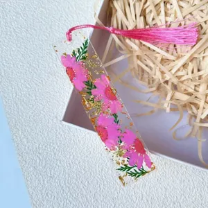 Macro detail of clear resin bookmark featuring real pink flowers and gold flakes.