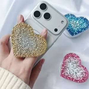 Detailed close-up of a sparkling heart-shaped rhinestone phone grip in gold and silver finish.