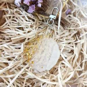 Close-up of a handmade round resin keychain with gold flakes in gift packaging
