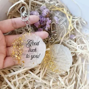 Detailed macro view of a round epoxy resin keychain with gold flakes and lucky text