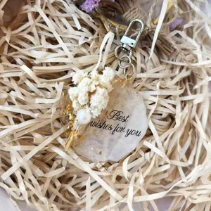 Detailed close-up of a resin keychain with dried flowers, pearl and gold leaf flakes