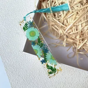 Close-up of handmade resin bookmark featuring real blue dried flowers and gold foil flakes.
