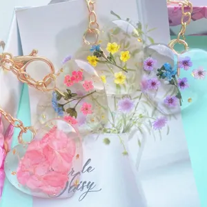 Close-up of heart-shaped resin keychains with real dried flowers and gold flakes.