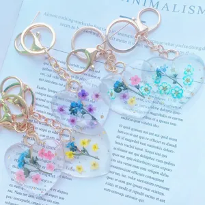 Macro detail of heart-shaped resin keychains with real dried flowers and gold flakes.